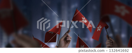 Hong Kong flags in their hands on a blurred urban background 132641692