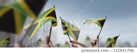 Jamaica flags in their hands on a blurred urban background Jamaica flags in their hands on a blurred urban background 132641706