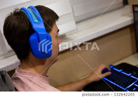 Average computer gamer. Bright headphones and gaming chair. Modern conditions for playing video games from home. Online communication via headphones and in game communication 132642205