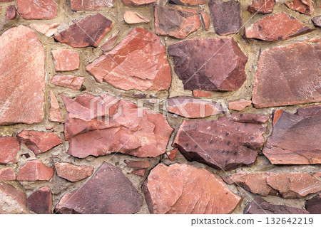 The wall of large raw granite stones of red color, background granite non-uniform The wall of large raw granite stones of red color, background granite non-uniform 132642219