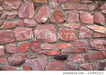 The wall of large raw granite stones of red color, background granite non-uniform The wall of large raw granite stones of red color, background granite non-uniform 132642223