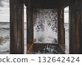 Waves crashing beneath an old pier in motion. 132642424