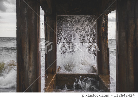 Waves crashing beneath an old pier in motion. Waves crashing beneath an old pier in motion. 132642424