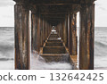 Symmetrical view under a pier with calm sea waves. 132642425
