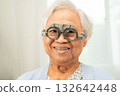 Optometrist checking Asian elderly woman ophthalmic vision eye test and using optical trial frame. 132642448
