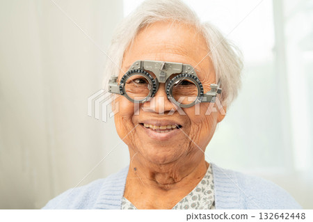 Optometrist checking Asian elderly woman ophthalmic vision eye test and using optical trial frame. 132642448