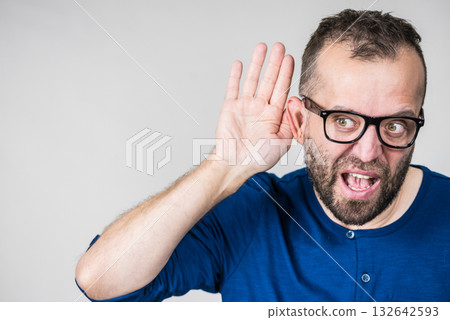 Man eavesdropping with hand close to ear 132642593
