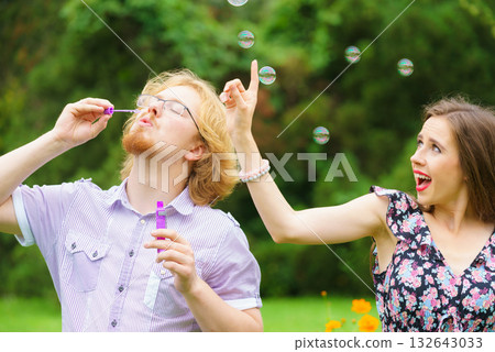 Couple blowing soap bubbles, having fun Couple blowing soap bubbles, having fun 132643033