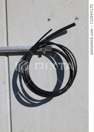 Black wire is hanging from a wall Black wire is hanging from a wall 132643170