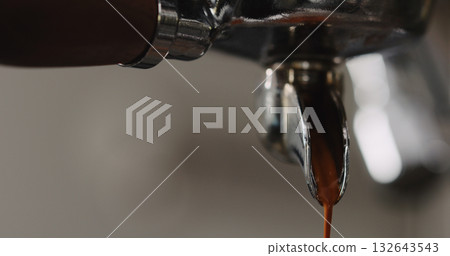 pulling espresso shot with single spout portafilter from coffee machine closeup 132643543