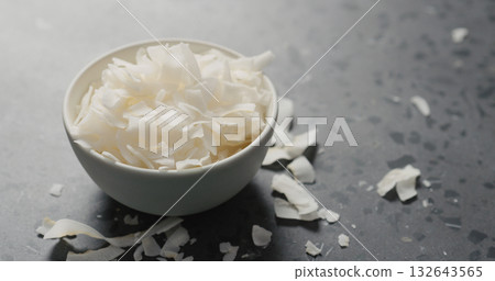coconut chips in white bowl on terrazzo surface coconut chips in white bowl on terrazzo surface 132643565