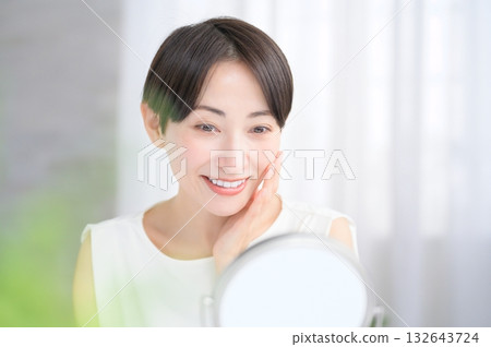 Japanese woman checking her skin in the mirror Japanese woman checking her skin in the mirror 132643724