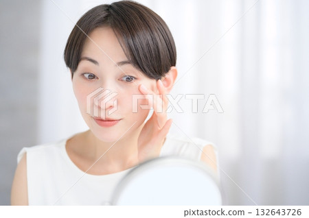 Japanese woman checking her skin in the mirror 132643726