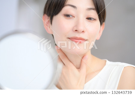 Japanese woman checking her skin in the mirror Japanese woman checking her skin in the mirror 132643739