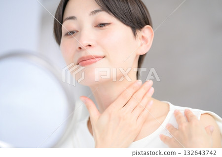 Japanese woman checking her skin in the mirror Japanese woman checking her skin in the mirror 132643742