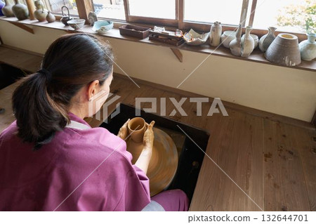一位婦女背對著陶輪製作陶器。 132644701