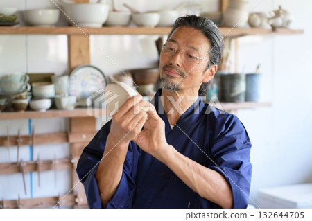 一位資深陶藝家正在查看作品。 132644705