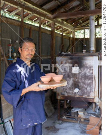 A veteran potter standing in front of his kiln A veteran potter standing in front of his kiln 132644709
