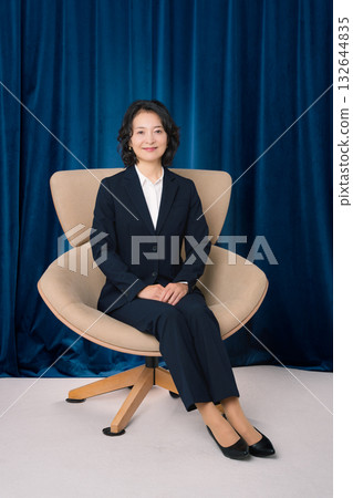 Middle-aged businesswoman sitting on a large chair Middle-aged businesswoman sitting on a large chair 132644835