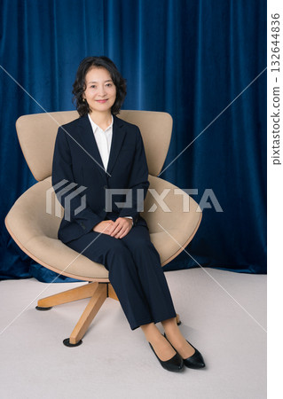 Middle-aged businesswoman sitting on a large chair Middle-aged businesswoman sitting on a large chair 132644836