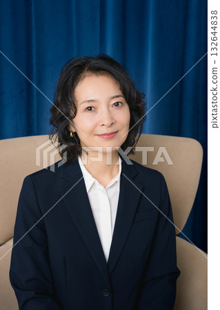 Middle-aged businesswoman sitting on a large chair Middle-aged businesswoman sitting on a large chair 132644838