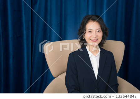 Middle-aged businesswoman sitting on a large chair Middle-aged businesswoman sitting on a large chair 132644842