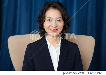 Middle-aged businesswoman sitting on a large chair Middle-aged businesswoman sitting on a large chair 132644923