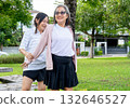 Asian senior woman stand and help her friend to do stretching back of arm and shoulder in garden with day light. 132646527
