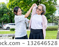 Asian senior woman stand and help her friend to do stretching arm and shoulder in garden with day light. 132646528