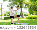Wide shot of Asian senior woman stand and help her friend to exercise with yoga in garden with day light. 132646534