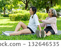 Asian senior woman sit on mat and help her friend to relax or stretching in garden with day light. 132646535