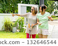 Asian senior woman discuss with friend and hold tools to decorate the garden of her house. 132646544