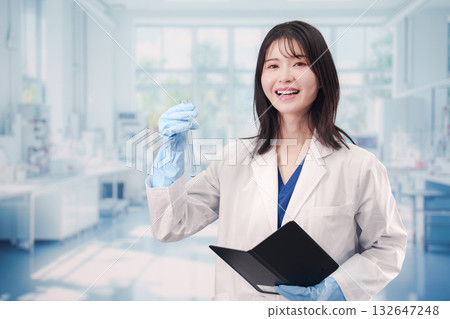 一位年輕女子在實驗室的試管裡操作化學物質。 一位年輕女子在實驗室的試管裡操作化學物質。 132647248