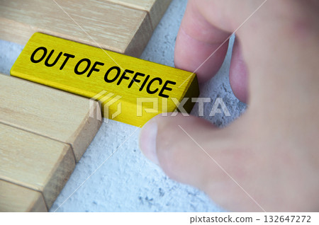 Hand pulling out a yellow wooden block with out of office text on. Getaway or on a vacation concept. Hand pulling out a yellow wooden block with out of office text on. Getaway or on a vacation concept. 132647272