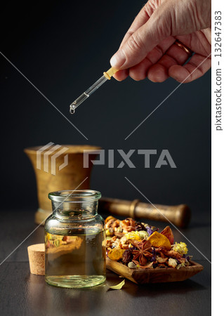 Dropping essential oil or herbal tincture into a small bottle. 132647383