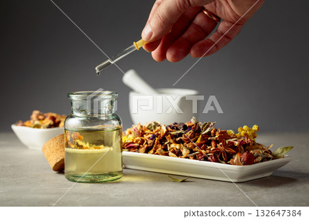 Dropping essential oil or herbal tincture into a glass bottle. Dropping essential oil or herbal tincture into a glass bottle. 132647384