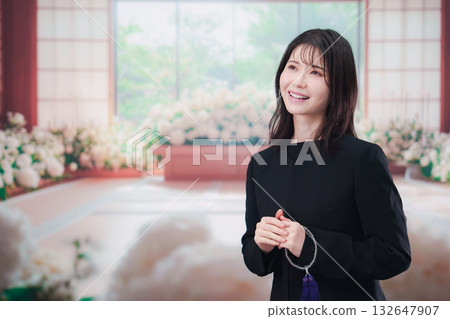 Young woman wearing mourning clothes and holding prayer beads at a funeral Young woman wearing mourning clothes and holding prayer beads at a funeral 132647907