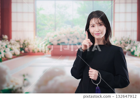 Young woman wearing mourning clothes and holding prayer beads at a funeral Young woman wearing mourning clothes and holding prayer beads at a funeral 132647912