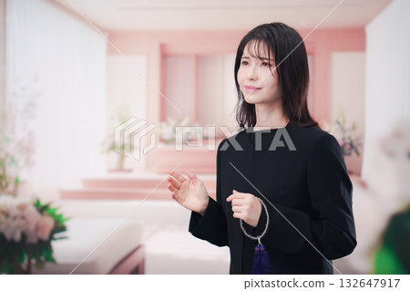 Young woman wearing mourning clothes and holding prayer beads at a funeral Young woman wearing mourning clothes and holding prayer beads at a funeral 132647917