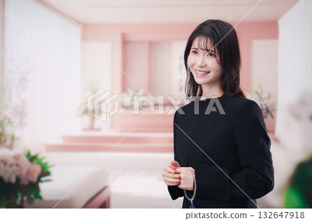 Young woman wearing mourning clothes and holding prayer beads at a funeral Young woman wearing mourning clothes and holding prayer beads at a funeral 132647918
