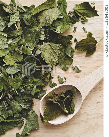 Loose dried blackcurrant leaves on wooden spoon and board, rustic kitchen texture and fragrant herbal tea mood Loose dried blackcurrant leaves on wooden spoon and board, rustic kitchen texture and fragrant herbal tea mood 132648002