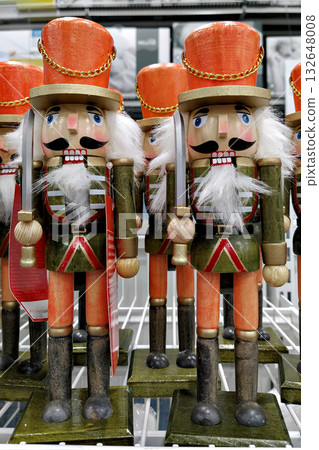 Wooden nutcracker soldiers holding swords, green uniforms and orange hats on store shelf, classic Christmas decor, bright festive mood 132648008