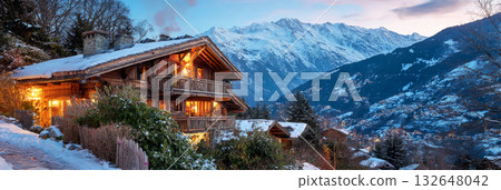 Experience a cozy winter vacation at beautiful chalets surrounded by snow-covered mountains. The warm lights contrast with the cold winter landscape, creating a serene atmosphere, banner 132648042