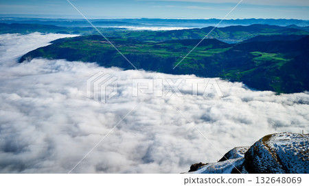Breathtaking view from the mountain peak overlooking clouds and lush greenery in the valley during daytime Breathtaking view from the mountain peak overlooking clouds and lush greenery in the valley during daytime 132648069