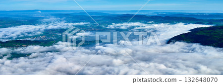 Beautiful landscape of rolling clouds covering the valley with distant mountains and clear blue sky Beautiful landscape of rolling clouds covering the valley with distant mountains and clear blue sky 132648070