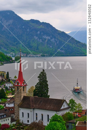 Picturesque view of a lake with a historical church and mountains in the background during a cloudy day Picturesque view of a lake with a historical church and mountains in the background during a cloudy day 132648082