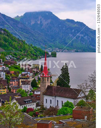 Charming village nestled by the lake surrounded by mountains in Switzerland on a cloudy day Charming village nestled by the lake surrounded by mountains in Switzerland on a cloudy day 132648083