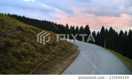 Winding road through forest hills at sunset with pink and blue sky in the background 132648109