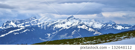 Stunning mountain landscape showcasing snow-capped peaks under a cloudy sky in a serene natural setting 132648112