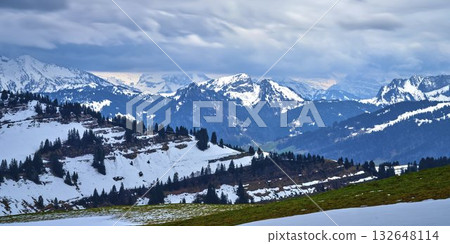 Snowy mountain landscape with dramatic clouds in a serene alpine setting during late winter 132648114